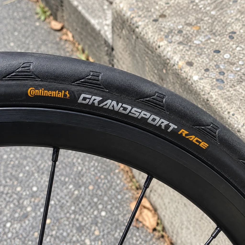 Lateral do pneu Continental Grand Sport Race preto montado na roda traseira de uma bicicleta de estrada